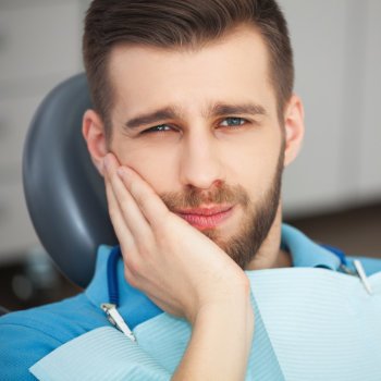 a young man is sitting with a toothache in the dental chair