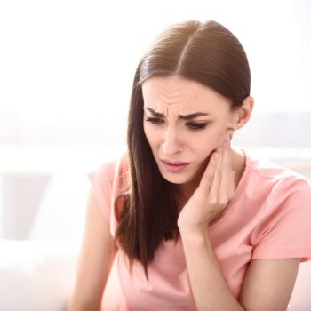 brunette suffering from severe toothache rubbing her cheek